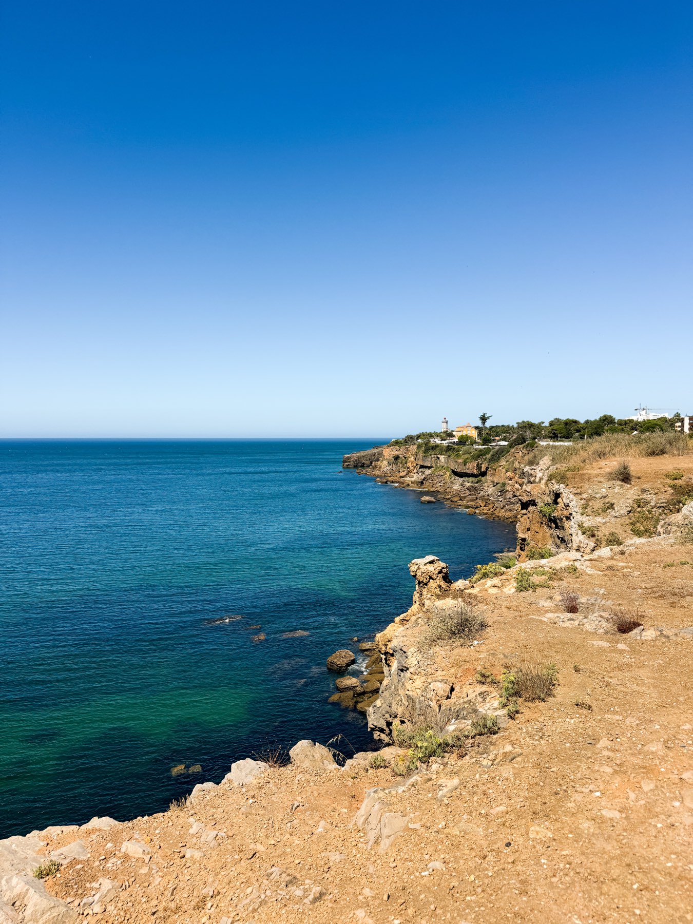 Cascais coastline with clear blue water and the Guia lighthouse under an August sky