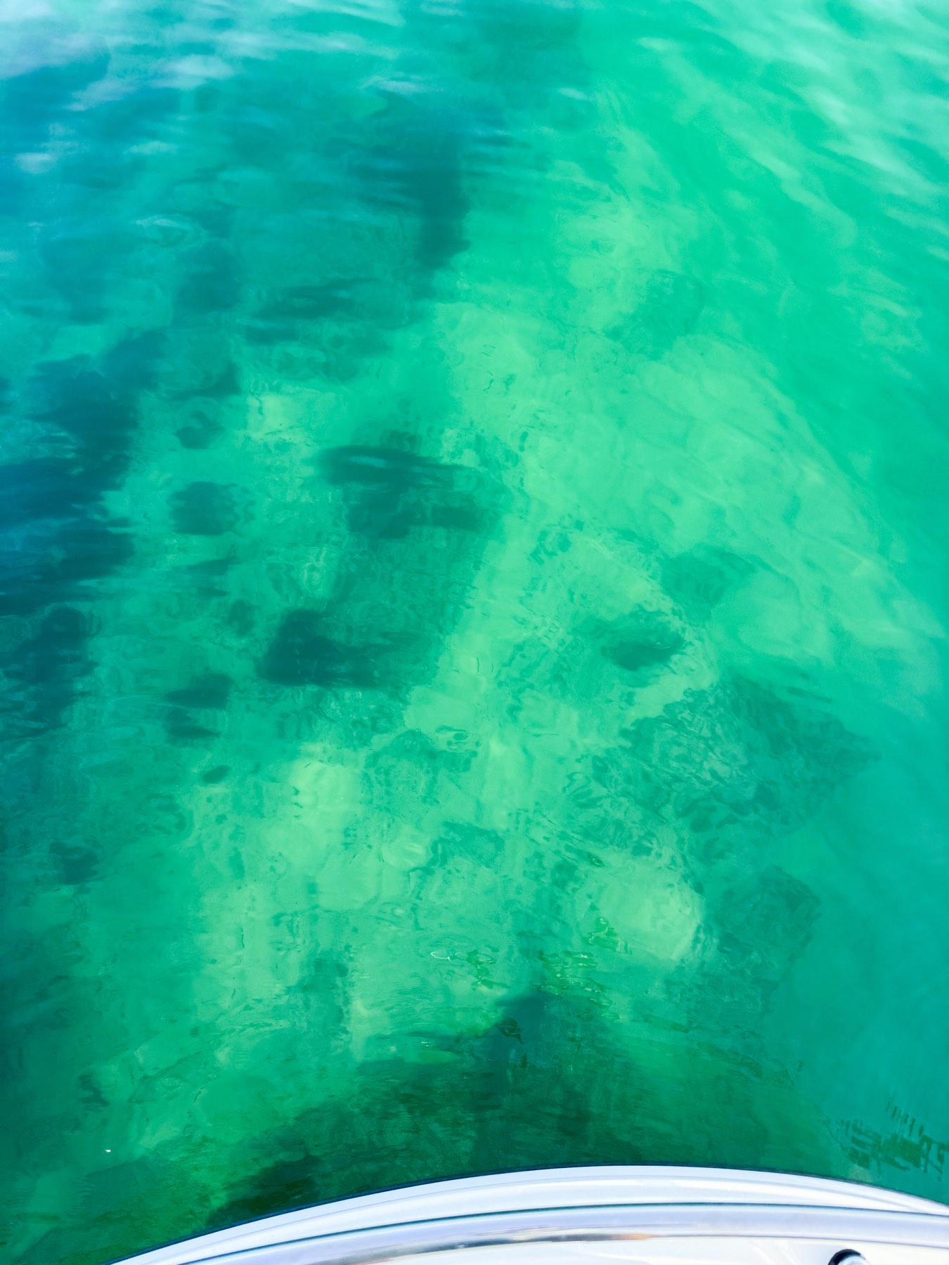 Seabed visible through clear tropical-green water on the Cascais coast in August